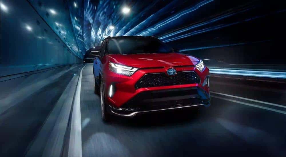 A popular Toyota RAV4 for sale near Bolingbrook, a red 2024 Toyota RAV4 Prime, is shown driving through a tunnel.