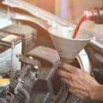 A mechanic is shown pouring transmission fluid into an engine during a transmission fluid change.