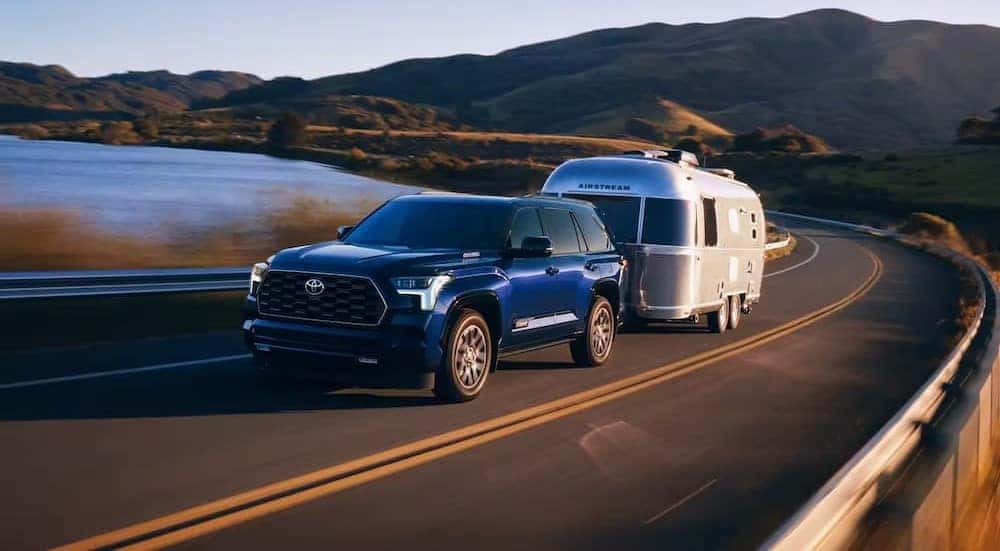A blue 2023 Toyota Sequoia is shown towing a trailer.
