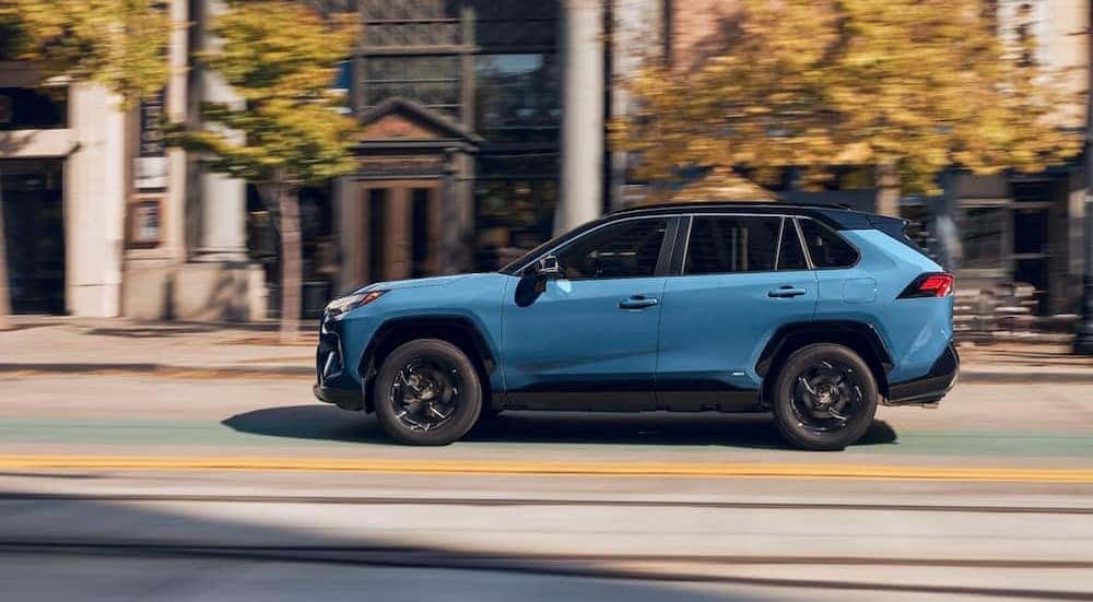 A blue 2024 Toyota RAV4 Hybrid is shown driving to visit a Toyota dealer near Orland Park.