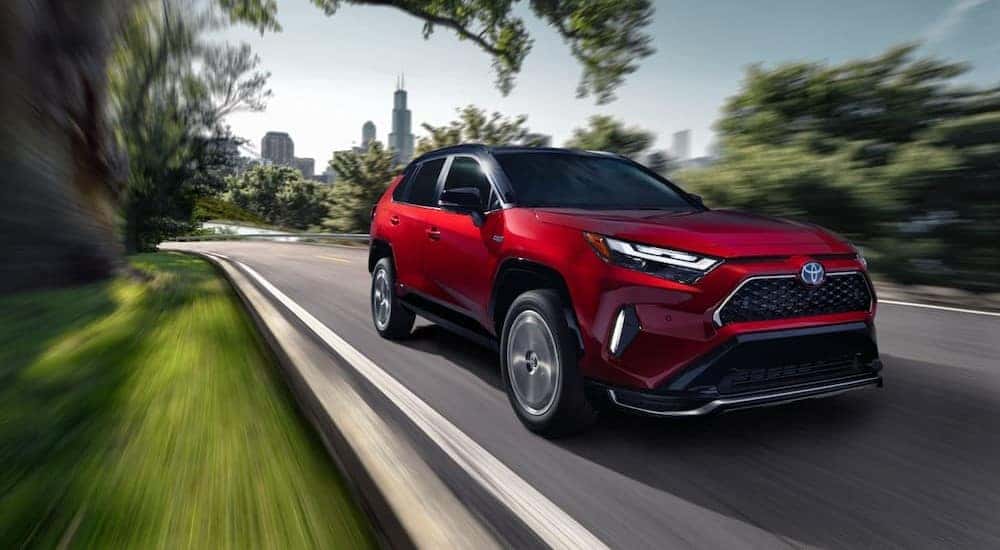 A red 2024 Toyota RAV4 Prime is shown driving to visit a Toyota dealer near Orland Park.