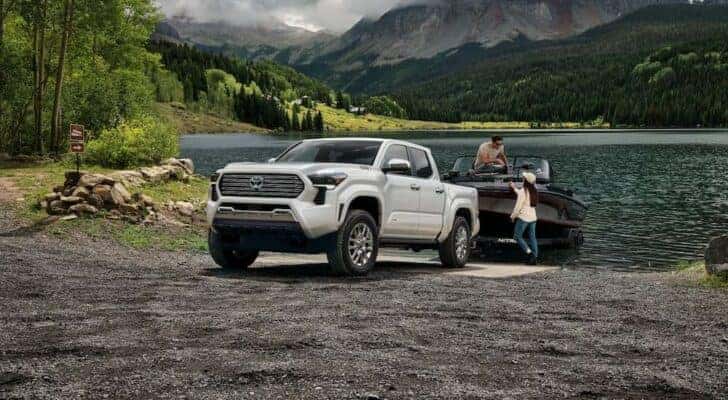 A white 2024 Toyota Tacoma Limited is shown towing a boat after visiting a Toyota Tacoma for sale near Joliet.