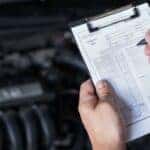 A person is shown holding a clipboard near an engine bay at a Toyota service center near Lockport.