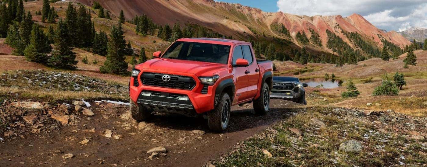 A red 2024 Toyota Tacoma TRD Off-road is shown driving near a mountain range.