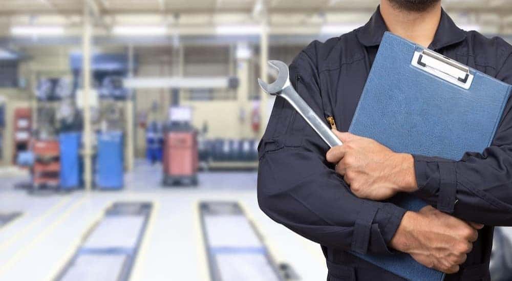 A mechanic is shown holding a wrench and a clipboard.