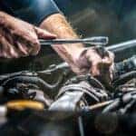 A mechanic is shown working on an engine.