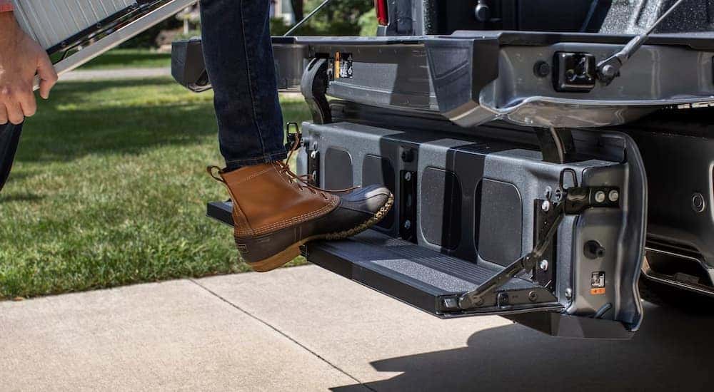 Stepping onto the full-width step of the Multi-Flex tailgate on a 2024 Chevy Silverado 1500 at a Chevrolet dealer.