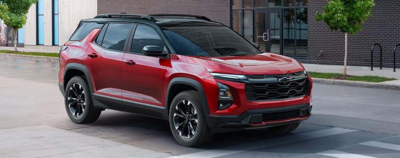 A red 2025 Chevy Equinox for sale angled right and driving in a city.