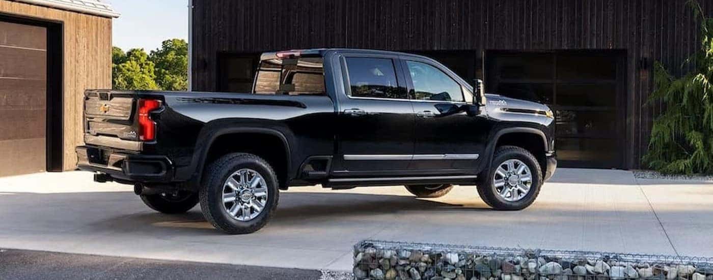 A black 2024 Chevy Silverado 3500 HD High Country is shown parked on a driveway.