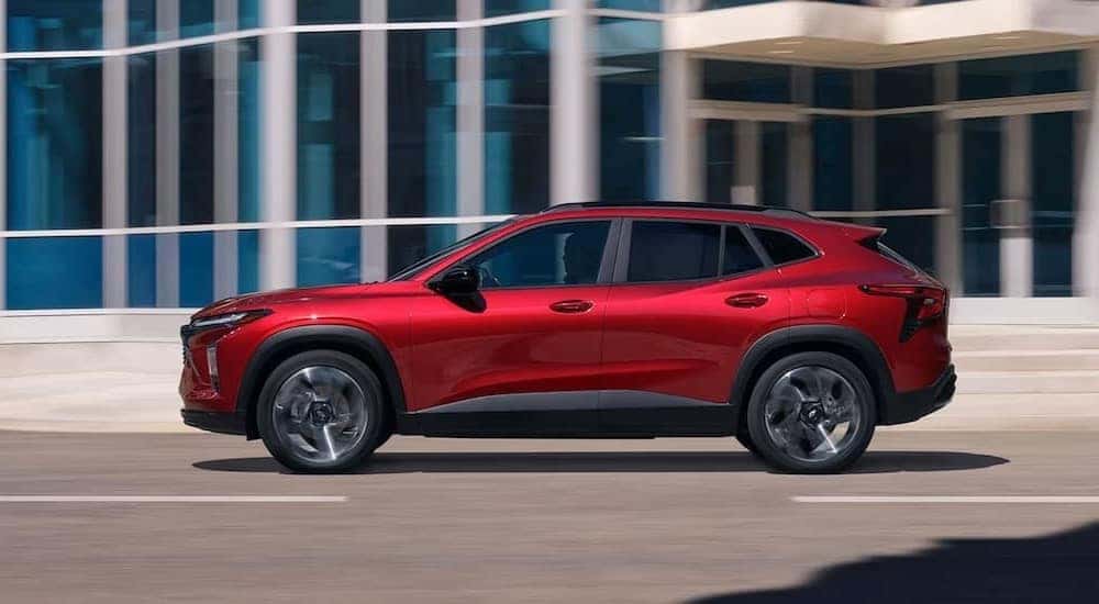 A red 2025 Chevy Trax RS is shown driving on a city street.