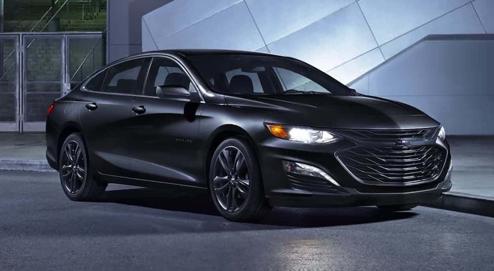 A black 2025 Chevy Malibu Midnight Edition parked outside a Chevy dealer near Karns.