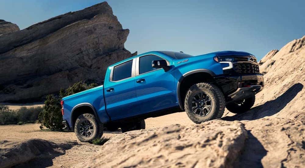 A blue 2025 Chevy Silverado 1500 ZR2 is shown parked on a rocky incline.