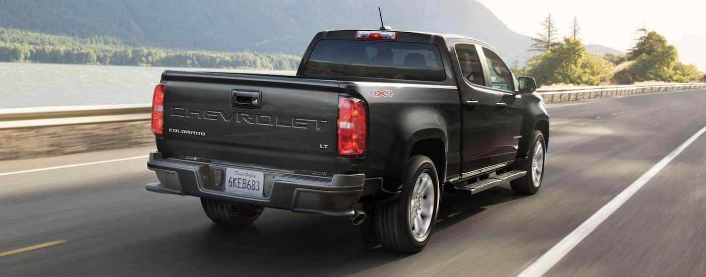 Rear view of a black 2022 Chevy Colorado LT driving down a road.