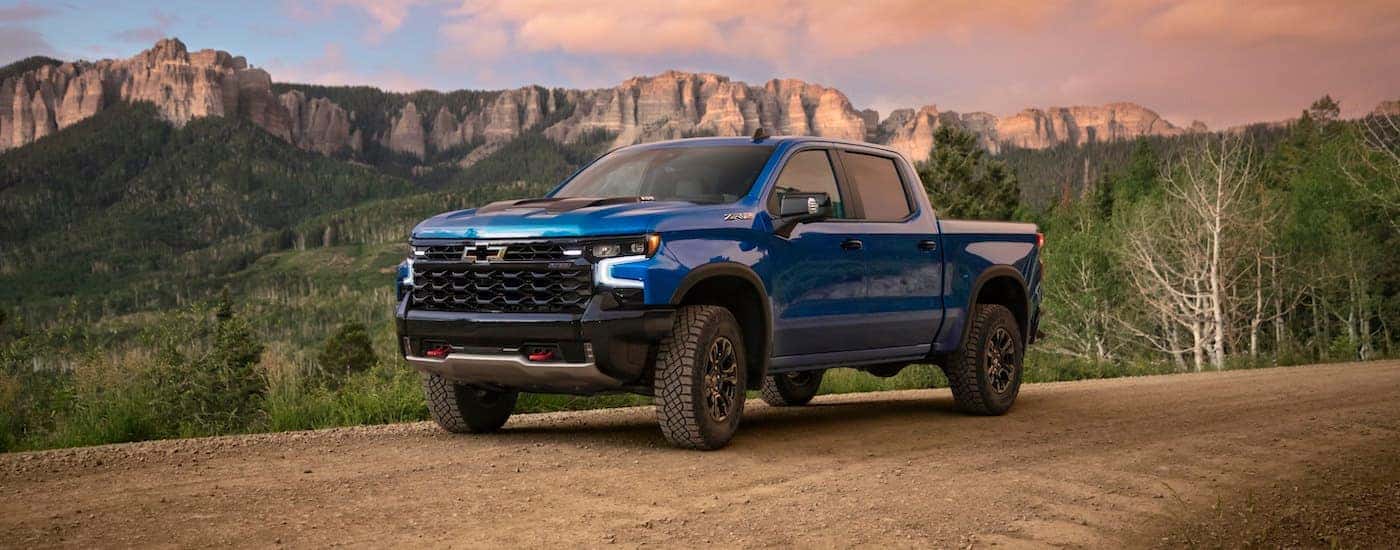 A blue 2023 Chevy Silverado 1500 ZR2 driving down a dirt road.