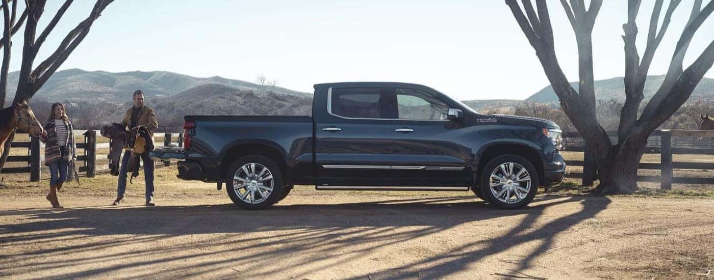A black 2024 Chevy Silverado 1500 High Country is shown parked near a tree after viewing a Chevy Silverado for sale.