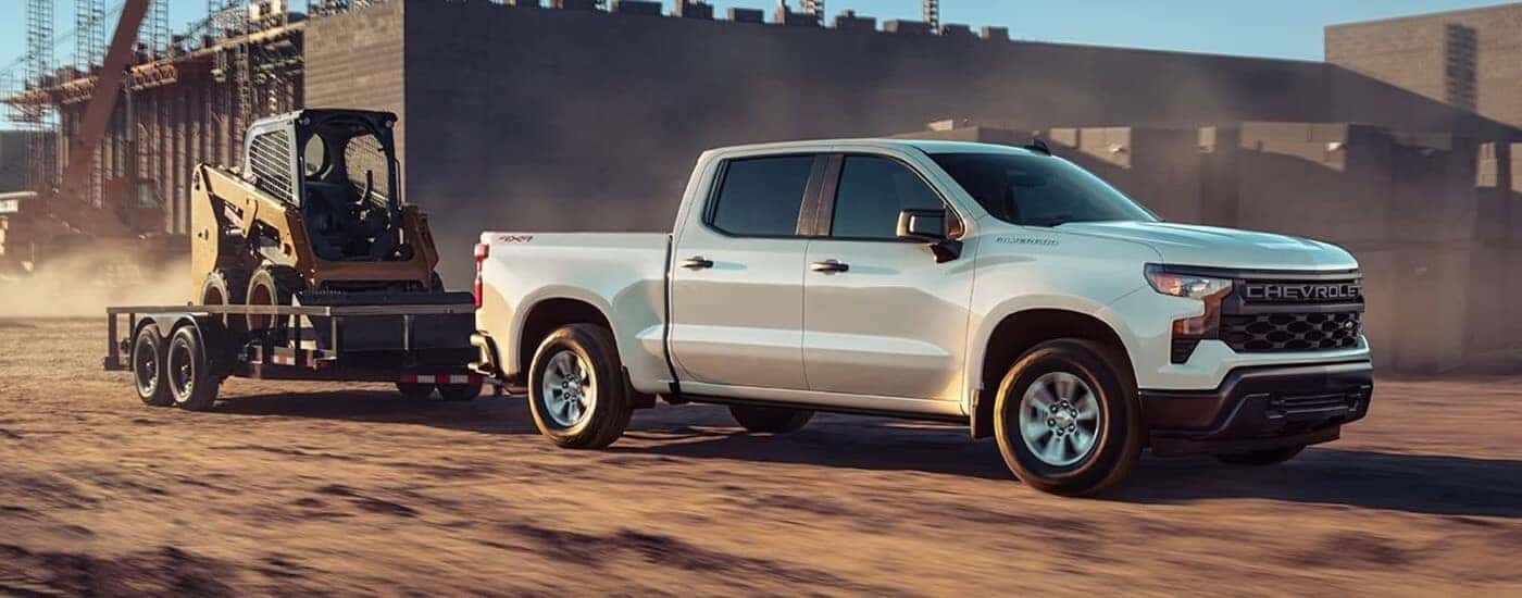 A white 2024 Chevy Silverado 1500 towing a trailer.
