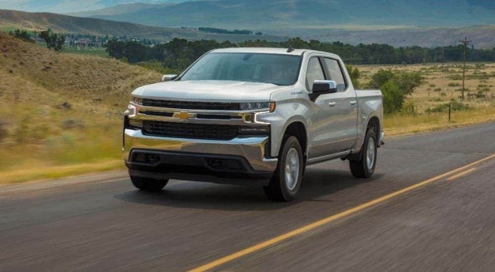 Used silver 2020 Chevy Silverado 1500 for sale driving down an open road.