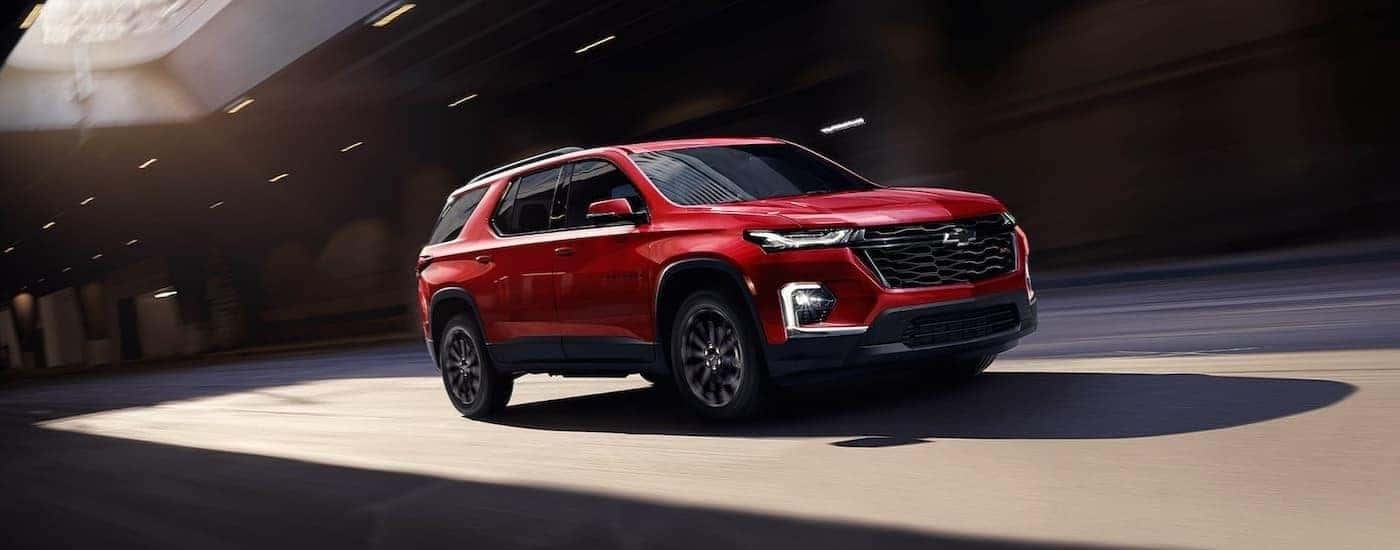 Red 2023 Chevy Traverse RS driving to see used SUVs for sale