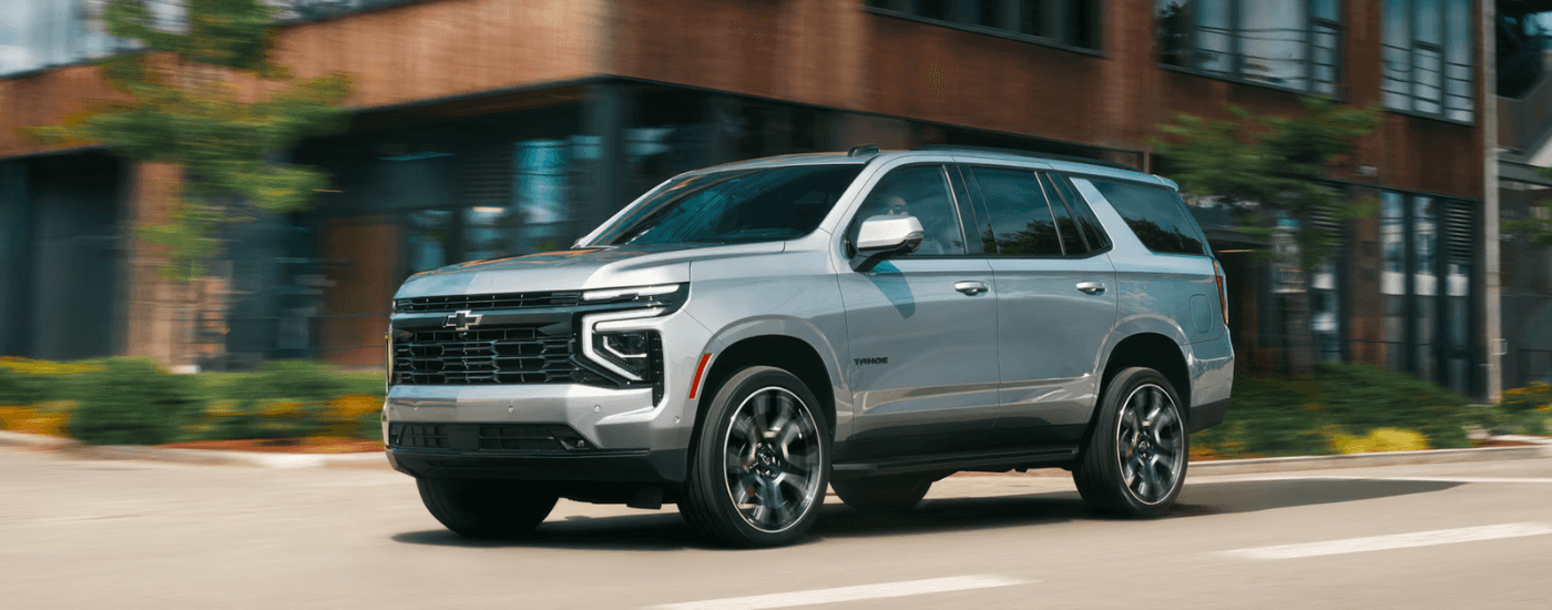 Silver 2026 Chevy Tahoe driving to see SUVs for sale
