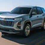 Silver 2026 Chevy Equinox driving down a road.