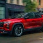 Red 2026 Chevy Equinox RS driving down a street.