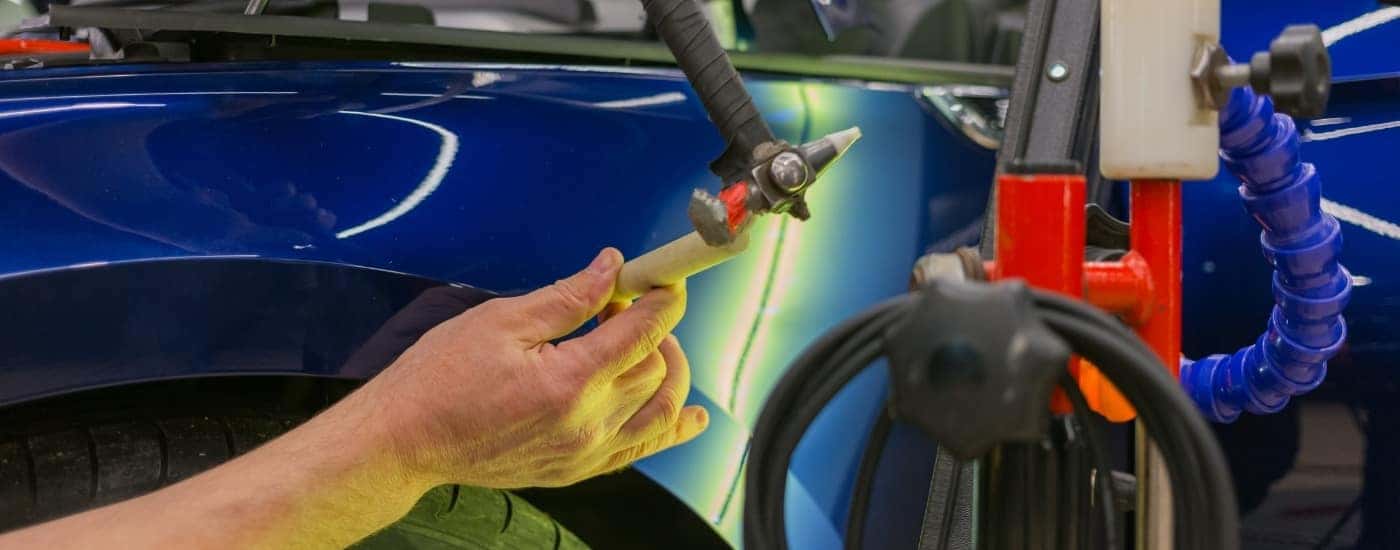 Auto body technician performing paintless dent repair