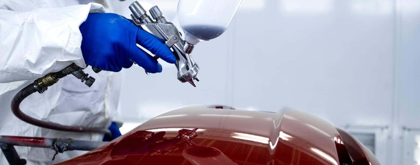 Auto body technician painting a red bumper
