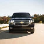 A black 2017 Chevy Suburban shown driving by a guard rail.