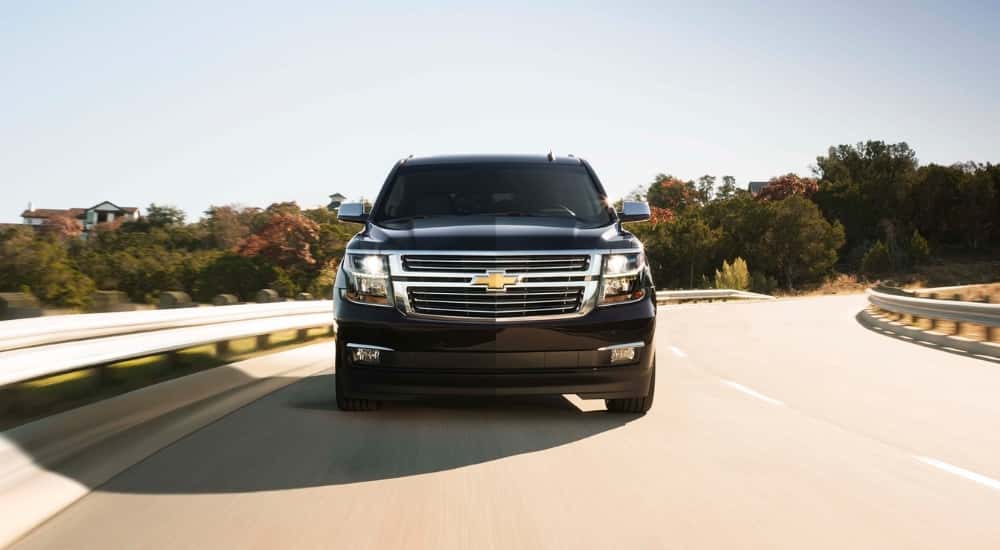 A black 2017 Chevy Suburban shown driving by a guard rail.