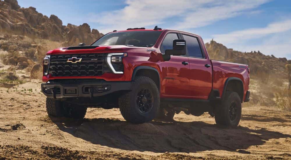 A red 2026 Chevy Silverado 2500 HD ZR2 Bison Edition shown parked on rocky terrain.