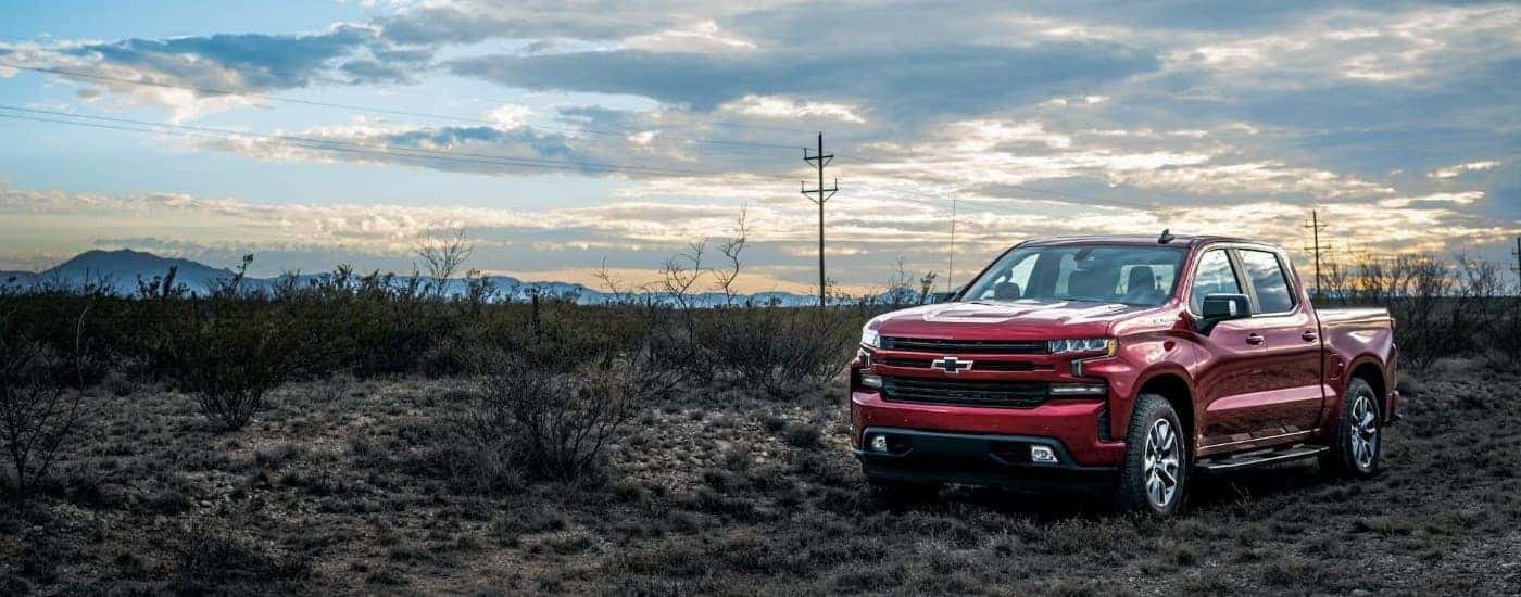 A red 2023 Chevy Silverado 1500 RST parked near a field.