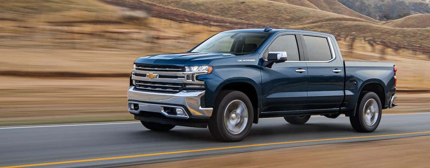 A blue 2021 Chevy Silverado 1500 driving in the country.