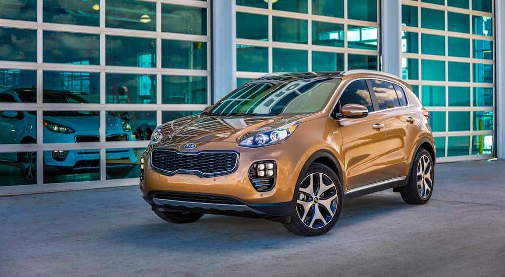 A gold 2019 Kia Sportage parked outside a modern garage.