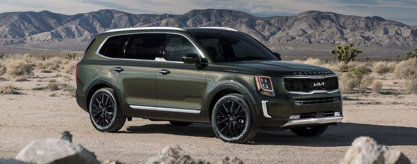 A green 2022 Kia Telluride is shown parked in a sandy region.