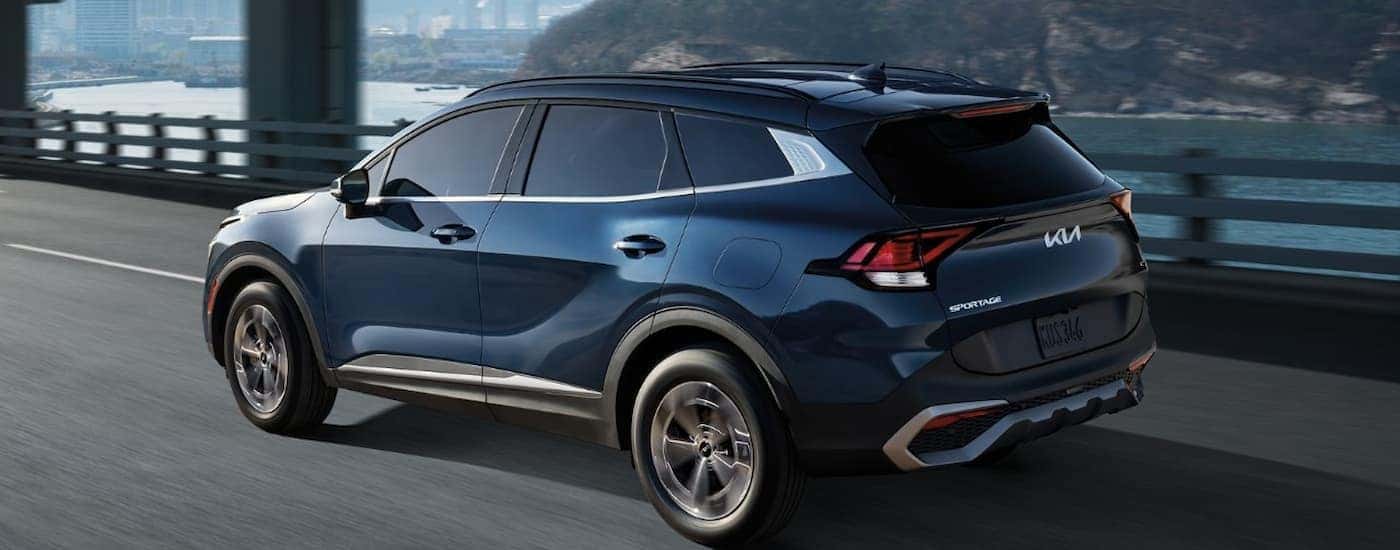 A blue 2023 Kia Sportage Hybrid is shown from a rear angle after leaving a used Kia dealer.