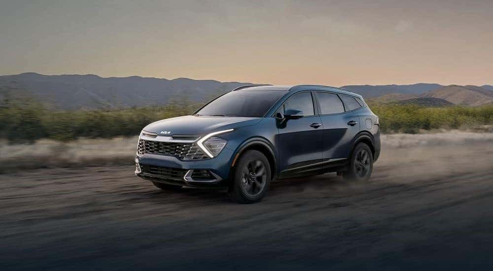 A blue 2024 Kia Sportage driving on a dusty trail.
