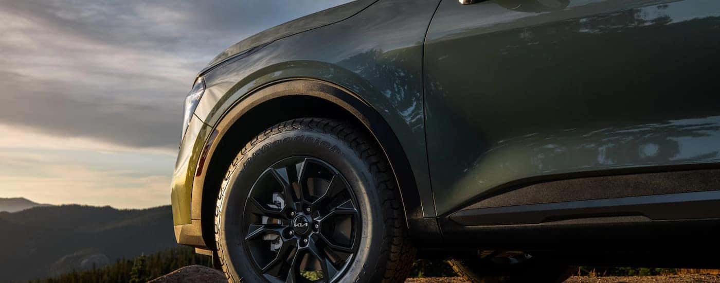 A close up of the side and tire on a green 2023 Kia Sportage for sale.