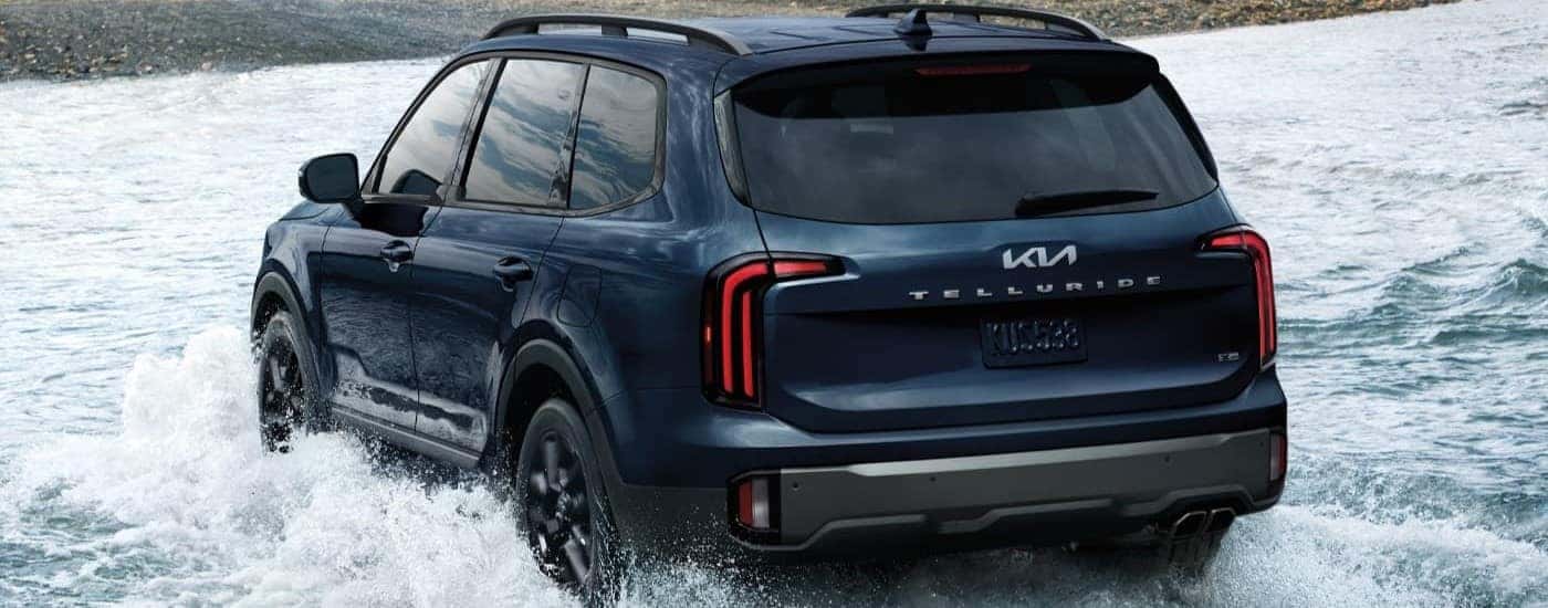 Rear view of a blue 2023 Kia Telluride fording a shallow river.