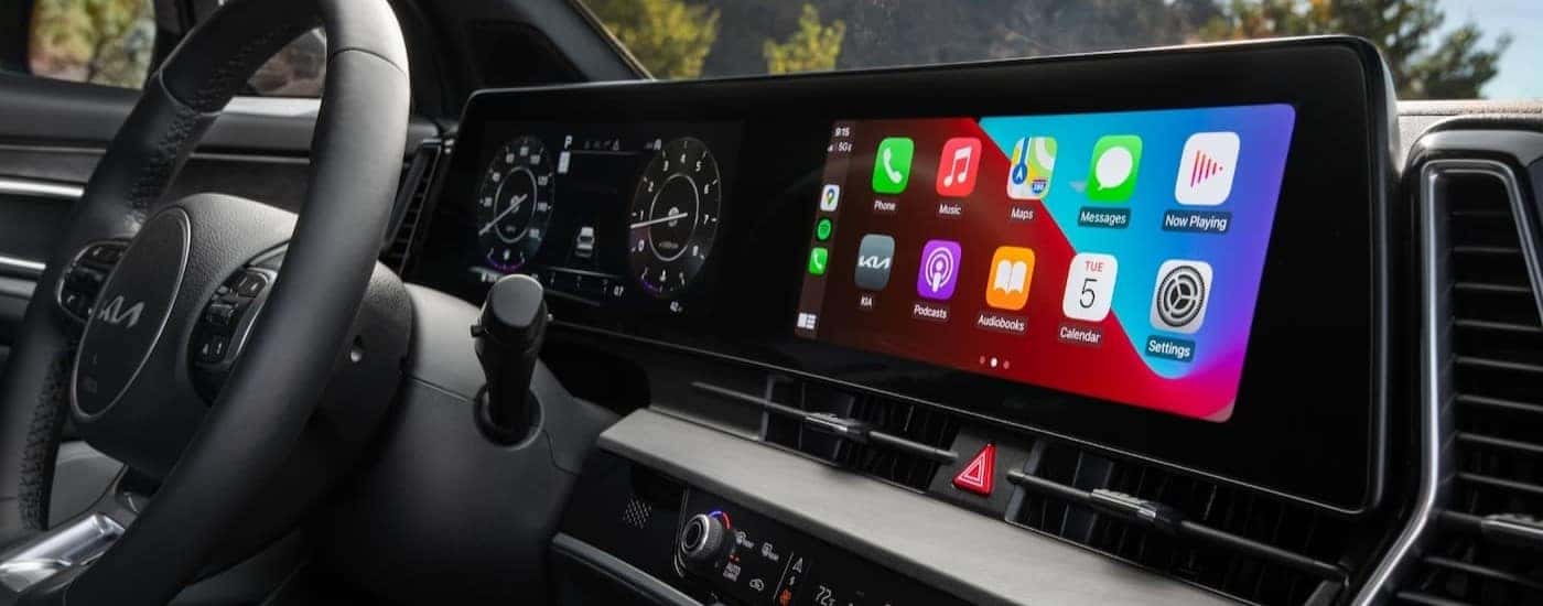 A close-up on the black wheel and infotainment screen in the interior of a 2024 Kia Sportage.