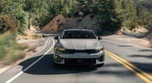 A gray 2024 Kia K5 is shown driving to a Kia dealer near Alcoa.
