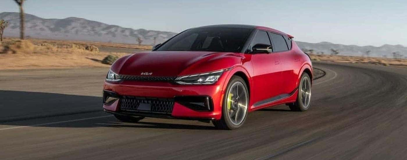 A red 2023 Kia EV6 is shown driving on a track.