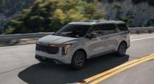 A gray 2025 Kia Carnival is shown driving to a Kia dealer in Knoxville.