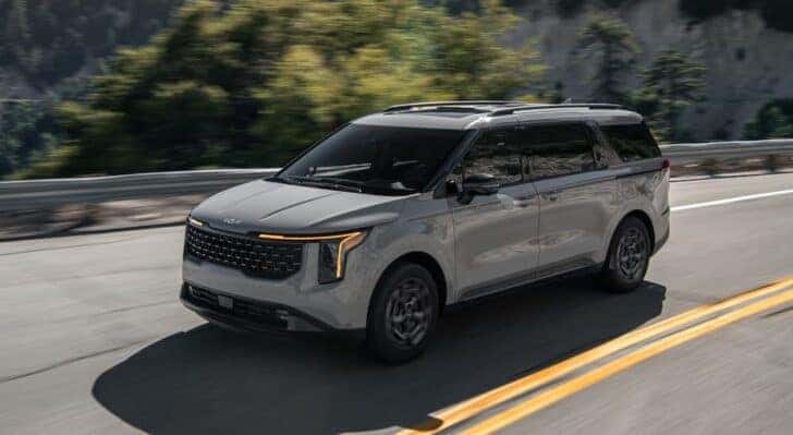 A gray 2025 Kia Carnival is shown driving to a Kia dealer in Knoxville.