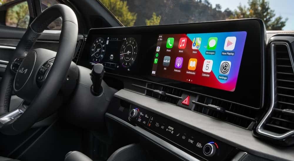 A close-up of the steering wheel and infotainment screen are shown in a 2025 Kia Sportage X-Pro Prestige.