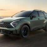 A green 2025 Sportage X-Pro Prestige is shown driving near an ocean after visiting a Kia dealer near Karns.