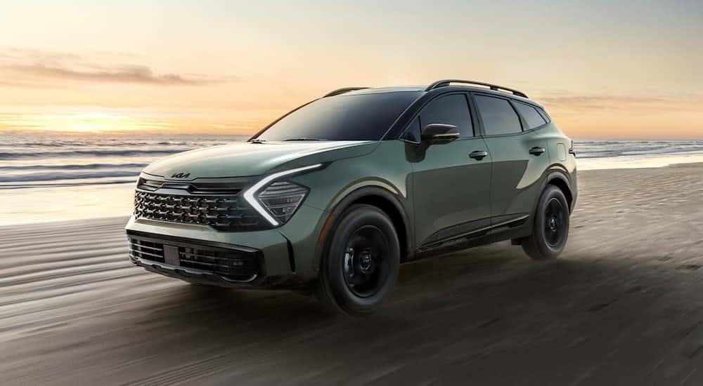 A green 2025 Sportage X-Pro Prestige is shown driving near an ocean after visiting a Kia dealer near Karns.