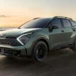 A green 2025 Kia Sportage on a beach,