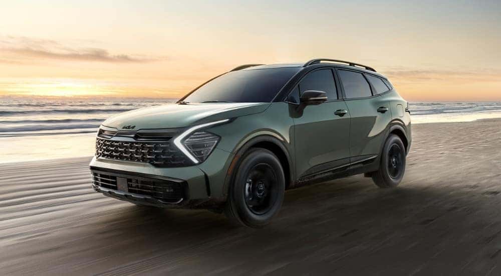 A green 2025 Kia Sportage on a beach,