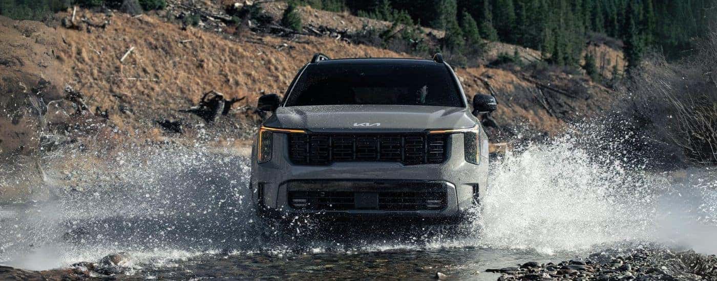 A grey 2024 Kia Sorento for sale near Jefferson City through a shallow river.