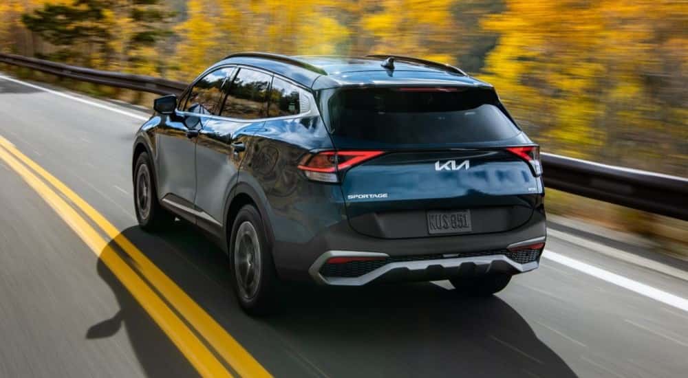 A dark blue 2023 Kia Sportage Hybrid driving down a highway